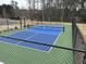 Bright blue and green community pickleball court with a black fence is surrounded by trees at 3032 Farm Tract Trl, Woodstock, GA 30189