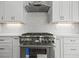 Close up of kitchen stove with white cabinets and mosaic tile backsplash at 1101 Cooks Farm Way, Woodstock, GA 30189