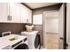 Modern laundry room with white cabinets, grey wall paint, and high-efficiency washer and dryer set at 7525 Homer Dr, Cumming, GA 30028