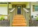 Inviting front porch with wood steps, modern gray and brown door, and natural landscaping at 2410 Macon Sw Dr, Atlanta, GA 30315