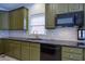 Close up of the kitchen features modern appliances and sleek black countertops and olive green cabinets at 5004 Duxford Se Dr, Smyrna, GA 30082