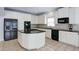 Spacious kitchen featuring white cabinets, black appliances, an island, and tiled floors at 5004 Duxford Se Dr, Smyrna, GA 30082