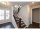 A well-lit foyer features gleaming hardwood floors, staircase with elegant banister, and a double glass door at 574 Sawnee Village Blvd, Cumming, GA 30040