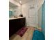 A stylish bathroom featuring a dark wood vanity, a white door with hooks, and turquoise accents on the bath mat at 1367 Midnight Ride Ct, Hampton, GA 30228