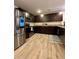 Modern kitchen with stainless steel appliances, dark cabinetry, and hardwood flooring at 1367 Midnight Ride Ct, Hampton, GA 30228