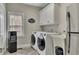 Laundry room featuring modern washer and dryer units, sink, and white cabinets at 5810 Ripplestone Nw Ct, Acworth, GA 30101