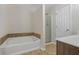 Bathroom with a soaking tub, glass shower, and vanity with wood cabinets at 6000 Suttles Sw Dr, Atlanta, GA 30331