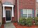 A close-up of a brick townhome entrance with a black door and manicured shrubbery at 2612 Halligan Pointe, Riverdale, GA 30296