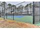 A tennis court with a green and blue surface is surrounded by a black chain link fence and tall trees at 3202 Monarch Pine Dr, Peachtree Corners, GA 30071