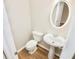 Neat powder room featuring hardwood floors, white fixtures and oval mirror at 506 Summer Pl, Norcross, GA 30071