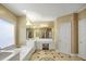 Elegant primary bathroom featuring double sinks, a soaking tub, and a vanity area, all illuminated by stylish lighting at 910 Renaissance Way, Roswell, GA 30076