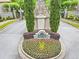 Community entrance featuring a stone gatehouse, flower beds, and well-maintained landscaping at 910 Renaissance Way, Roswell, GA 30076