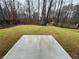 A grassy backyard featuring a bare trees and a concrete pad at 111 Woodside Ct, Temple, GA 30179