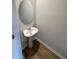 Compact powder room featuring a pedestal sink, oval mirror and wood-look floors at 111 Woodside Ct, Temple, GA 30179