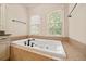 Bright bathroom featuring a built-in tub, tile surround, and two windows with natural light at 130 Staddlebridge Ave, Canton, GA 30114