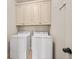 Practical laundry area with white washer and dryer, and overhead cabinets for storage at 130 Staddlebridge Ave, Canton, GA 30114