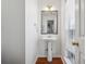 Half bathroom featuring white pedestal sink, brushed brass fixtures, and hardwood flooring at 4030 Brushy Creek Way, Suwanee, GA 30024