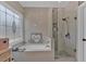 Bright bathroom featuring a soaking tub next to a shower with glass doors and unique, decorative window at 5382 Whitaker Nw Trl, Acworth, GA 30101