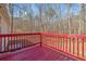 Wooden back deck with red painted railing overlooks natural wooded backyard at 95 Riverbrooke Trl, Covington, GA 30016