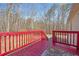 Back deck with red painted wood, outdoor rug, and backyard landscape views at 95 Riverbrooke Trl, Covington, GA 30016