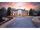 Stately brick mansion with manicured landscaping, long paved driveway, and grand entrance at sunset at 4615 Northside Dr, Atlanta, GA 30327