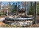 Rustic fire pit with stone surround and seating in a wooded setting at 4615 Northside Dr, Atlanta, GA 30327
