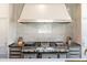 Close-up of chef's range with an exhaust hood, marble backsplash, and stainless steel appliances at 4615 Northside Dr, Atlanta, GA 30327