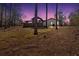 Backyard features an ample yard bordered by mature trees with a twilight sky at 360 Chimney Ct, Fairburn, GA 30213