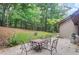 View of the outdoor patio featuring a table with four chairs in a wooded backyard at 3625 N Berkeley Lake Nw Rd, Berkeley Lake, GA 30096