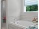 Bathroom showcasing a bathtub with tiled backsplash, adjacent to a walk-in shower and window views at 3790 Chattahoochee (Lot 33) Rd, Cumming, GA 30041