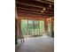 Bright, unfinished living room area featuring wooden flooring, window framing and a backyard view at 3790 Chattahoochee (Lot 33) Rd, Cumming, GA 30041