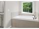 Bright bathroom features a tiled soaking tub underneath a window with a view of the trees at 3790 Chattahoochee (Lot 33) Rd, Cumming, GA 30041