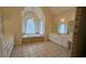 Luxurious bathroom boasting a soaking tub under an arched window, flanked by double vanities and tile floors, offering a spa-like experience at 1205 Peeksville Rd, Locust Grove, GA 30248