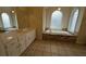 Large bathroom featuring a jacuzzi tub, elegant cabinetry, and arched windows with a tiled floor at 1205 Peeksville Rd, Locust Grove, GA 30248