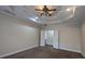 Bedroom featuring plush carpeting, a tray ceiling with fan, and double doors leading to bathroom at 1205 Peeksville Rd, Locust Grove, GA 30248