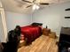 Simple bedroom with hardwood floors, ceiling fan and a bed with red blanket at 1536 Hunters Cv, Auburn, GA 30011