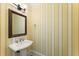 Stylish powder room with a pedestal sink, elegant mirror, and attractive striped wallpaper at 3128 Lower Roswell Rd, Marietta, GA 30068