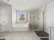 Bright bathroom featuring a soaking tub, tiled shower, and a window at 372 Garnet Dr, Acworth, GA 30101