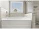 White soaking bathtub, gray tiled walls, and a view of the window with blinds at 372 Garnet Dr, Acworth, GA 30101