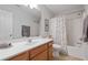 Bright bathroom featuring a shower-tub combo with a decorative curtain, and a wooden vanity with a white countertop at 3862 Memphis Dr, Suwanee, GA 30024