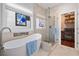 Sunlit bathroom featuring a standalone tub, glass shower, and closet at 3862 Memphis Dr, Suwanee, GA 30024