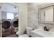 Contemporary bathroom with a laundry closet, marble-style accent wall, and modern fixtures at 1445 Wheatfield Dr, Lawrenceville, GA 30043