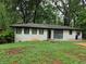 Ranch style home with white painted brick and dark trim, surrounded by mature trees at 3490 Primrose Pl, Decatur, GA 30032