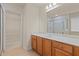 Bright bathroom featuring wood cabinets, a large mirror, and a glass shower with bright, neutral tile surround at 5480 Beaver Ridge Dr, Cumming, GA 30040