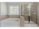 A bathroom features a soaking tub, glass-enclosed shower, and large window at 1011 Buckhorn Bnd, Locust Grove, GA 30248