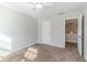 A carpeted bedroom with a ceiling fan, white walls, and a door to the hallway at 1011 Buckhorn Bnd, Locust Grove, GA 30248