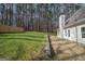 Large backyard featuring a retaining wall, lush green grass, and a wooded area creating a private, serene outdoor space at 255 Olde Oak Dr, Jonesboro, GA 30238