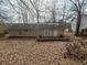 Back view of home features siding, a small patio area, and a leaf-covered yard at 5676 Marbut Rd, Lithonia, GA 30058