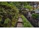 Landscaped stone walkway with lush greenery and a railing leading to a stone fireplace feature in the backyard at 121 17Th Ne St, Atlanta, GA 30309