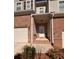 Townhome entryway with brick details and a white door, surrounded by lush landscaping at 1935 Manor Pointe Dr, Cumming, GA 30041